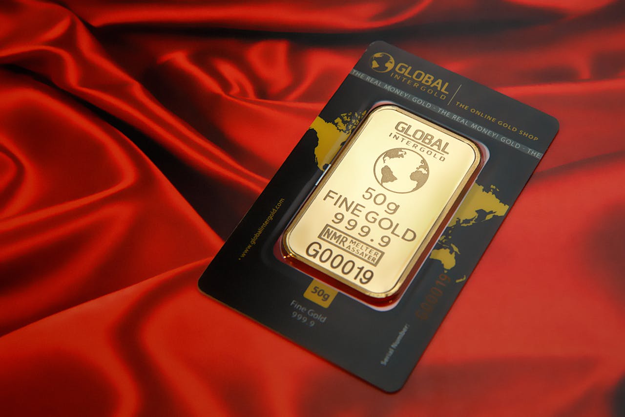 A 50g fine gold bar displayed elegantly on a rich red fabric background, symbolizing wealth and luxury.